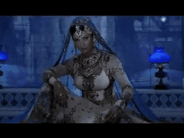 a woman in a white and silver dress with a blue veil on her head