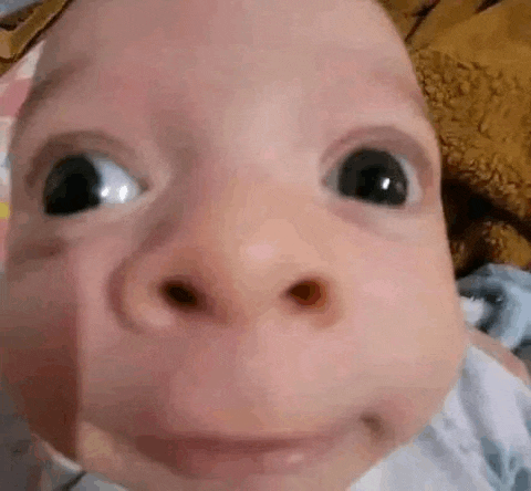 a close up of a baby 's face with a big nose making a funny face .