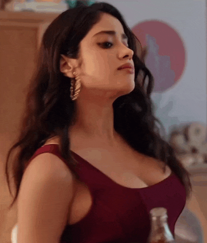 a woman in a red tank top is holding a bottle .