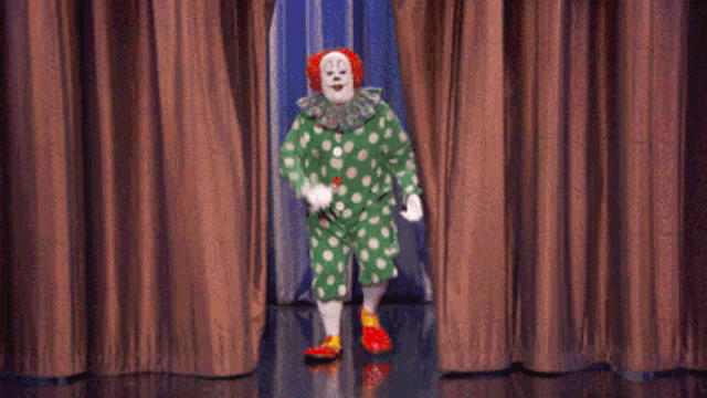 a clown in a green and white polka dot outfit is standing on a stage