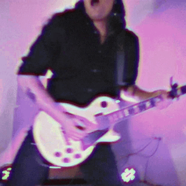 a blurry image of a man playing a guitar with a purple background