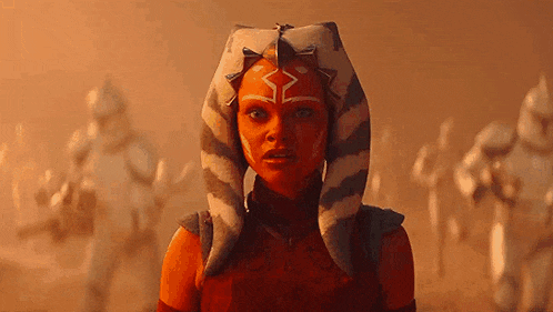 a woman in a red costume with a striped headband is standing in the desert .