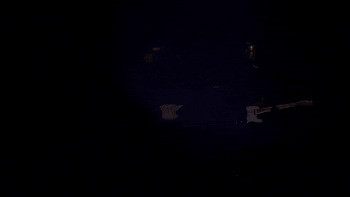 a dark room with a few lights shining through a hole in the wall