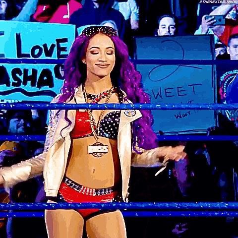 a woman with purple hair is standing in a wrestling ring with a sign that says `` love sasha '' behind her .