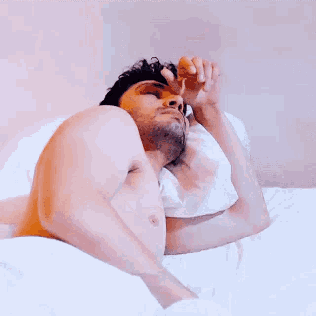 a shirtless man is sleeping on a bed with a white blanket