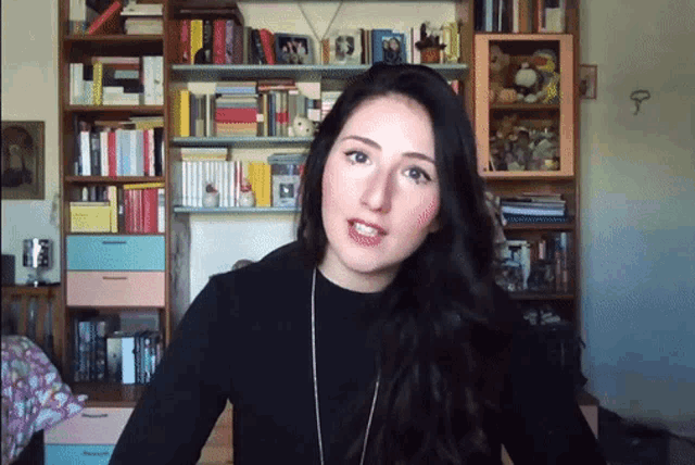 a woman is standing in front of a bookshelf with a picture of a man on it