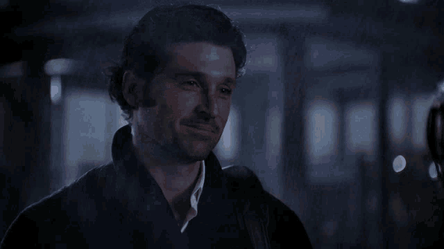 a man wearing a black jacket and a white shirt is smiling