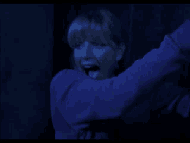 a woman in a purple sweater is screaming in the dark