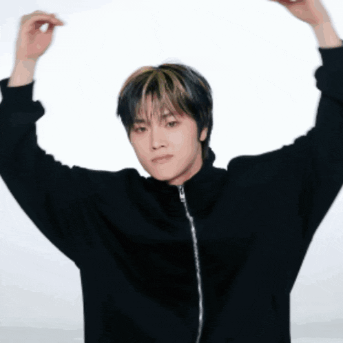 a young man in a black jacket is standing with his arms outstretched