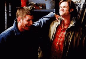 two men are standing next to each other and one is laughing .