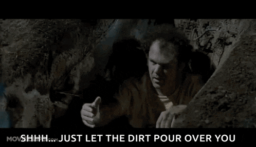 a man is crawling out of a hole in the dirt in a movie .