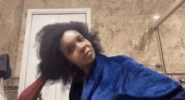 a woman in a blue robe is brushing her hair .