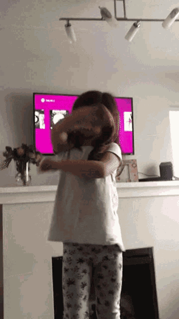 a little girl is dancing in front of a tv that says xbox