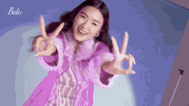 a woman in a purple coat giving the peace sign