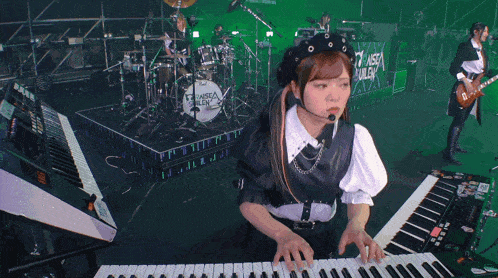 a girl is playing a keyboard in front of a drum set that says " between ruler "