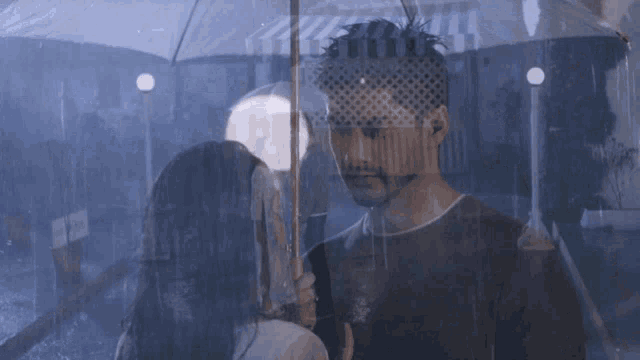 a man and woman are standing under an umbrella in the rain at night