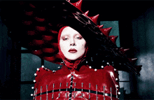 a woman in a red latex outfit with spikes on her hat