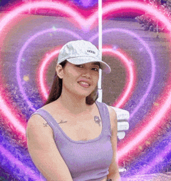 a woman in a purple tank top and white hat is smiling