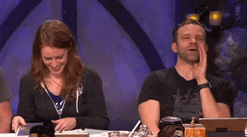 a man and a woman are sitting at a table with the words wow written on the screen