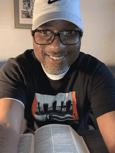 a man wearing a nike hat is reading a bible