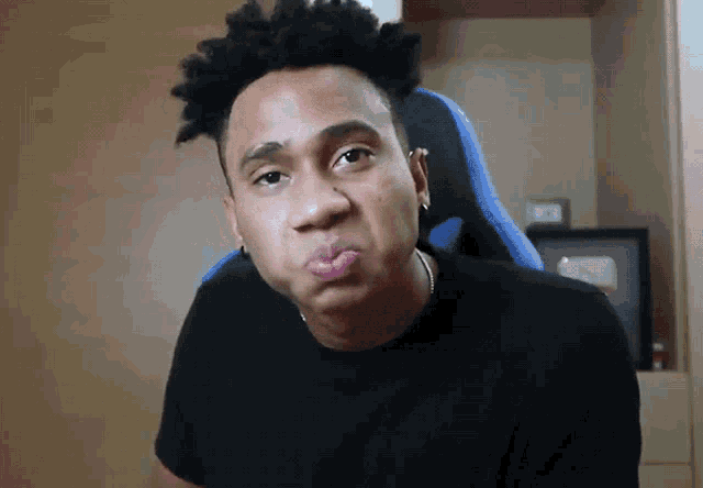 a man wearing a black shirt and a blue chair making a funny face