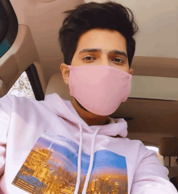 a man wearing a pink face mask and a white hoodie