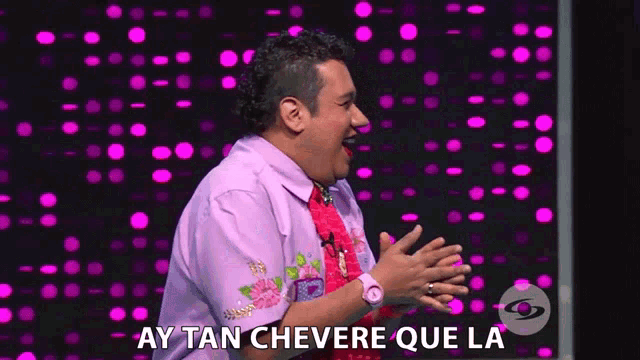 a man in a purple shirt says ay tan chevere que la on a purple background
