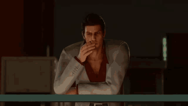 a man in a suit and red shirt is smoking a cigarette while standing on a balcony .