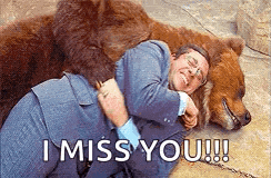 a man in a suit is hugging a large brown bear .