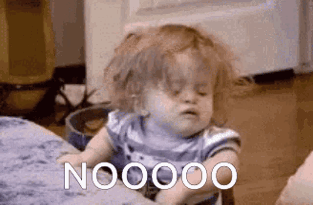 a little girl is sitting on a couch with the word nooooo written on the bottom .