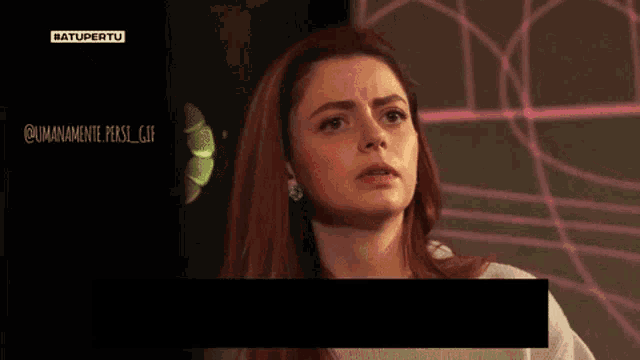 a woman with red hair and blue earrings is standing in front of a screen that says ' #atupertu ' on it