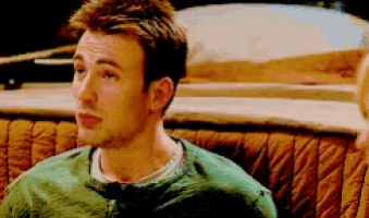 a man in a green sweater is sitting on a couch looking at something .