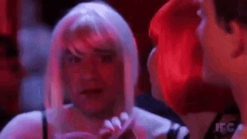 a man in a wig is standing next to a woman in a red dress .