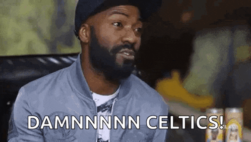 a man with a beard is sitting on a couch and saying `` damnnnn celtics ''