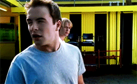 two young men are standing in front of a yellow wall