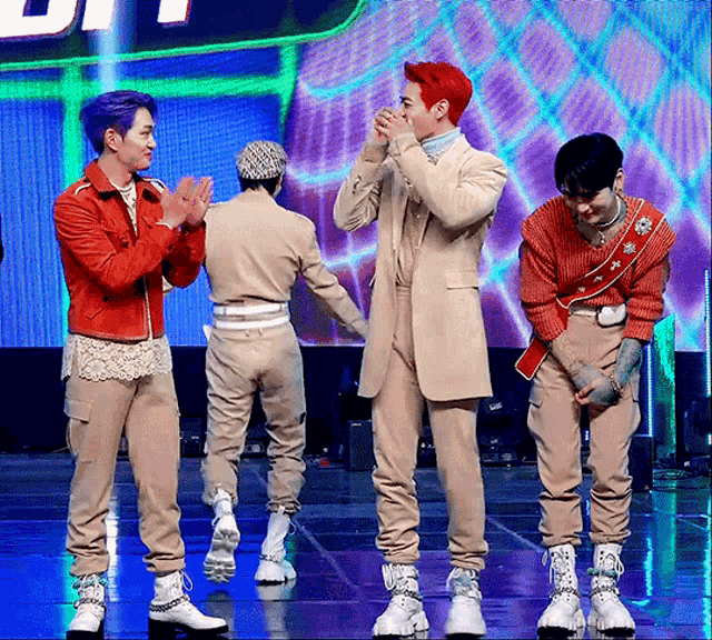 a group of men are standing on a stage and one of them has purple hair