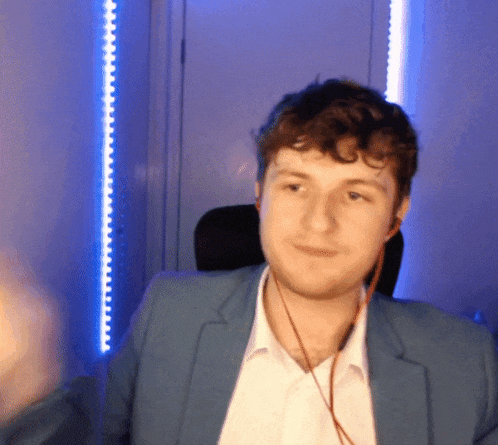 a man wearing a blue jacket and earbuds looks at the camera
