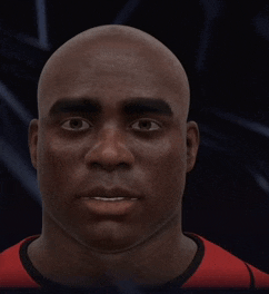 a bald man is wearing a red shirt and looking at the camera