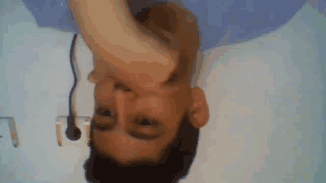 a man 's head is upside down with a plug plugged into the wall behind him