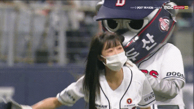 a woman wearing a mask is being greeted by a mascot with a doosan logo on his shirt