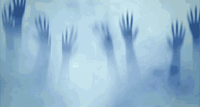 a group of ghostly hands are reaching out from behind a glass wall