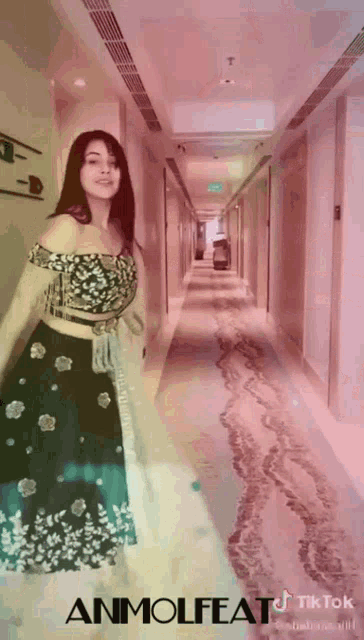 a woman in a dress is standing in a hallway with the words tiktok written on the bottom