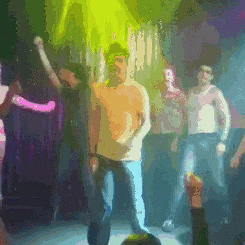 a man in a yellow shirt is dancing in a crowd of people