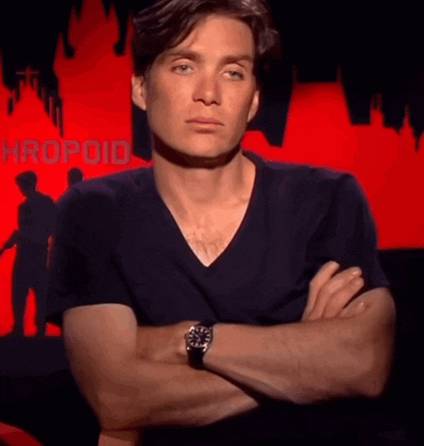a man stands with his arms crossed in front of a red background with the word hropoid on it