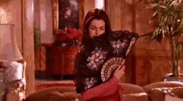 a woman is sitting on a couch holding a fan in a living room .