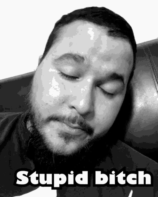 a man with a beard is sleeping on a couch with the caption stupid bitch