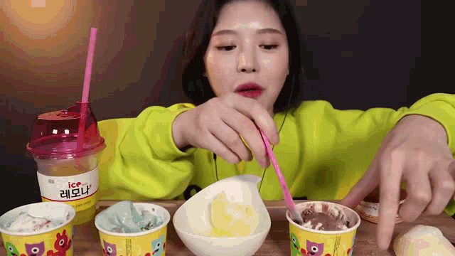 a woman in a green sweater is eating ice cream with a pink straw .