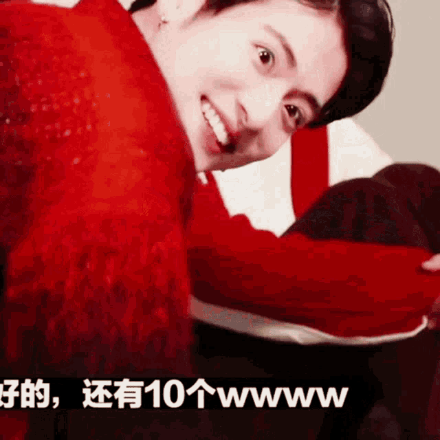 a man in a red sweater is smiling and looking at the camera while sitting on a couch .