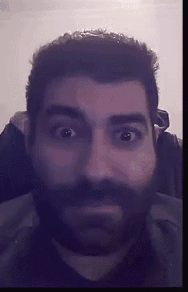 a close up of a man 's face with a beard and a surprised look on his face .