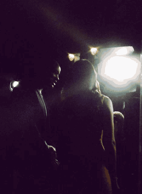 a man and a woman in a dark room with a light shining on them
